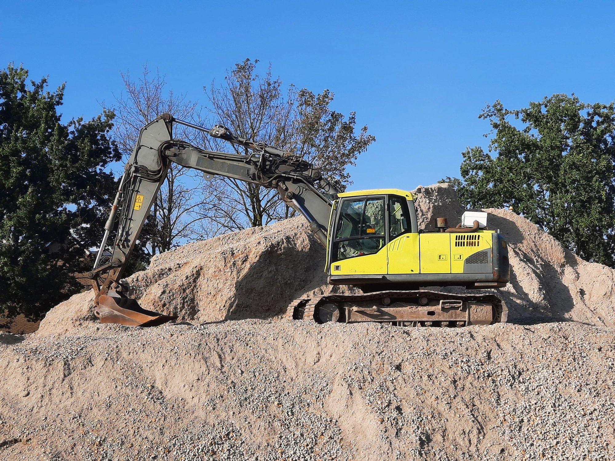 Yellow tracked excavator working on a gravel mound