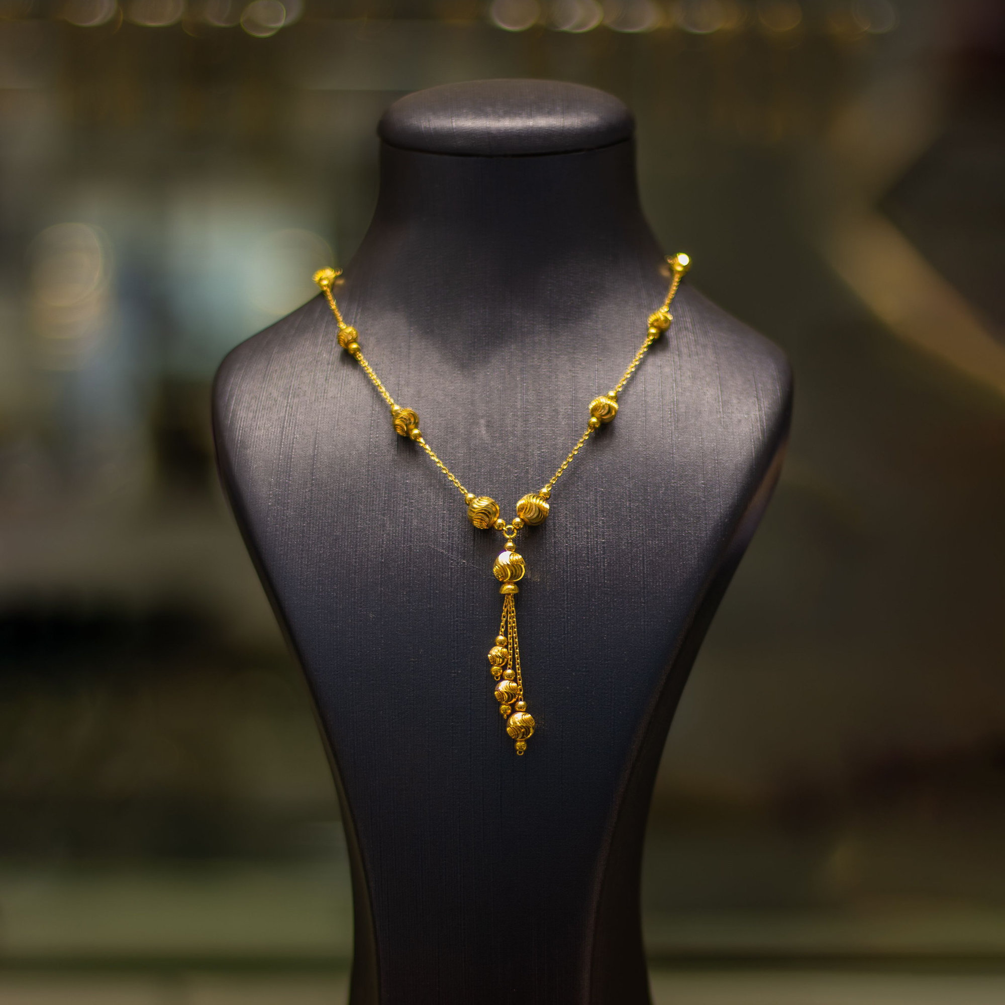 Gold necklace on a black display mannequin